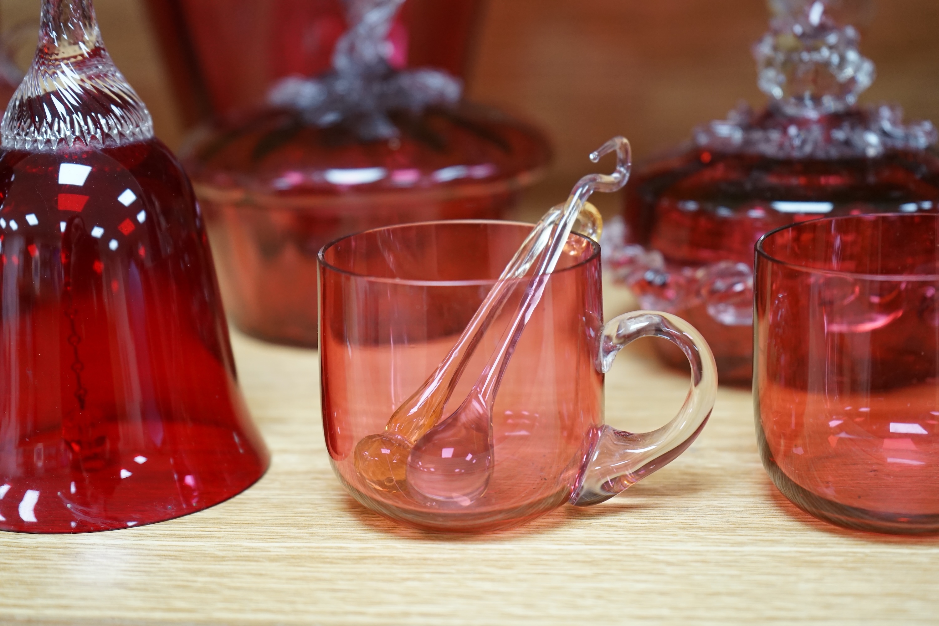 Mixed cranberry glassware to include jugs, glasses, jars and a comport, largest 23cm high. Condition - fair to good